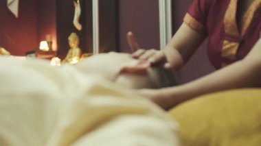 Taylandlı masöz bir adamın kafasına masaj yapar. Yakışıklı çocuk masaj yatağında yatıyor. Yakın plan..