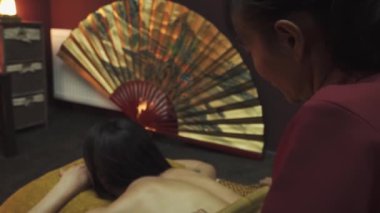 Spa yatağında uzanan güzel bir kadının vücudunda bambu masaj terapisi çubukları vardır. Yakın plan..
