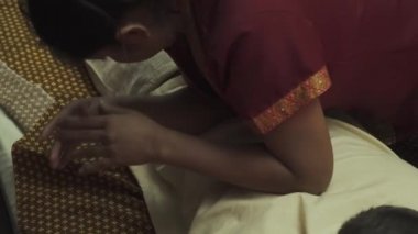 Taylandlı masöz bir erkeğe sırt masajı yapar. Çocuk masaj için yatağa uzanır ve sırt masajı yaptırır. Yakın plan..