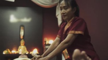 İki masöz bitkisel kese kullanan bir adama Tayland masajı yapıyor. Yakın plan..