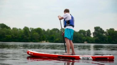 Yakışıklı genç adam nehir boyunca bir kanonun üzerinde yüzer..