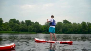 Yakışıklı genç adam nehir boyunca bir kanonun üzerinde yüzer. Güzel kız bir kanonun üzerinde durarak yüzer.