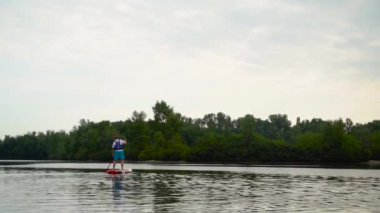 Genç adam nehir boyunca bir kanonun üzerinde yüzer..