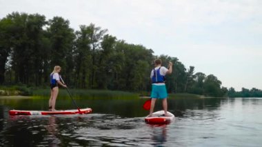 Çekici çift kıyıdaki kanoların üzerinde yüzüyor. Gençler aktif olarak suyun üzerinde dinleniyorlar..