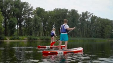 Güzel bir çift kıyı boyunca kanoların üzerinde yüzüyor. Gençler aktif olarak suyun üzerinde dinleniyorlar..