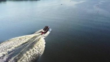 Sporcu adam uyandığında yüzüyor ve motorlu tekneye tutunuyor. Yukarıdan bak. Genç insanlar kanolarla önde yüzerler..