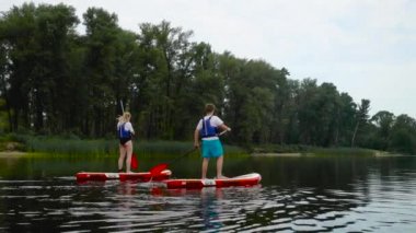 Çekici genç çift kıyı boyunca kanoların üzerinde yüzüyor. Gençler aktif olarak suyun üzerinde dinleniyorlar..