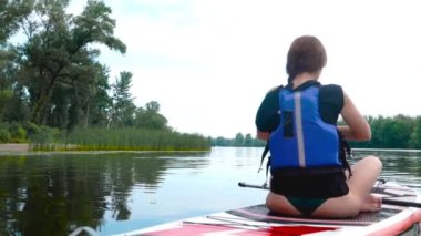 Güzel esmer bir kanoda oturuyor. Kız nilüfer çiçeğiyle meditasyon yapıyor..