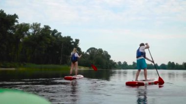 Güzel genç çift kıyıdaki kanoların üzerinde yüzüyor. Gençler aktif olarak suyun üzerinde dinleniyorlar..