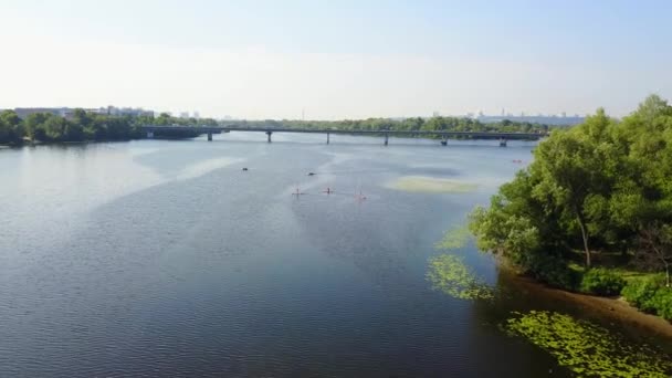 年轻人在河上划船 摄像机从上面下来 移动到皮划艇上 背景上的汽车桥 — 图库视频影像