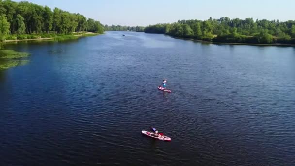 一对运动型夫妇在河里的皮划艇上漂浮着 照相机沿着河边移动 汽艇向照相机驶去 — 图库视频影像