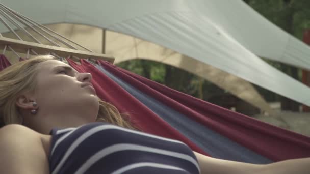 年轻的女士在室外的吊床上醒来 女孩在公园的吊床上休息 那女人在公园里小睡了一下 — 图库视频影像
