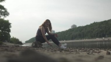 Genç kadın nehrin kıyısında oturuyor. Kadın dışarıda vakit geçiriyor. Dişi, güzel manzaraya hayran. Arkadan ateş ediyorlar.