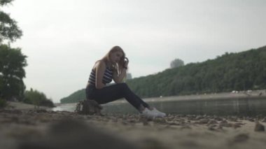 Genç kadın nehrin kıyısında oturuyor. Kadın dışarıda vakit geçiriyor. Dişi, güzel manzaraya hayran. Arkadan ateş ediyorlar.