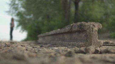 Taş blok dışarıda duruyor. Kadın silueti arka planda yürüyor. Kadın figürü bulanık.