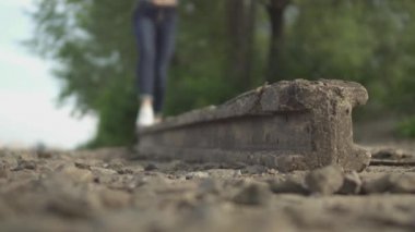 Kız bir taş blokta dengede duruyor. Kadın dışarıda vakit geçiriyor. Hanımefendi dikkatli adımlar atarak düşmemeye çalışıyor. Alttan ateş ediyorlar.