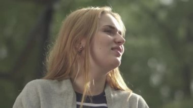 Komik kız kameraya gülümsüyor ve dışarıda öpüşmek için dudaklarını birleştiriyor. Genç bir kadın komik bir şekilde yüzünü buruşturuyor. Kadın dışarıda vakit geçiriyor.