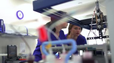 Laboratuvarda uyuşturucu üretimini kontrol eden mavi üniformalı ve lastik eldivenli iki genç kadın. Laboratuvarda araştırma yapıyorum. Bilim, meslek, sağlık konsepti