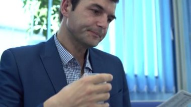 Olgun adam fiyat listesini okuyor ve plastik camdan su içiyor.