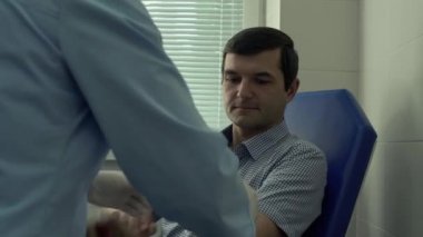 Arka plandaki koltukta oturan erkek hastanın kanını alan tanınmamış bir hemşire. Kan testi. Bilim, meslek, sağlık konsepti