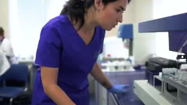 实验室里那个穿着蓝色制服和橡胶手套控制药品生产的年轻女人 在现代实验室进行研究 医疗保健 慢动作 — 图库视频影像