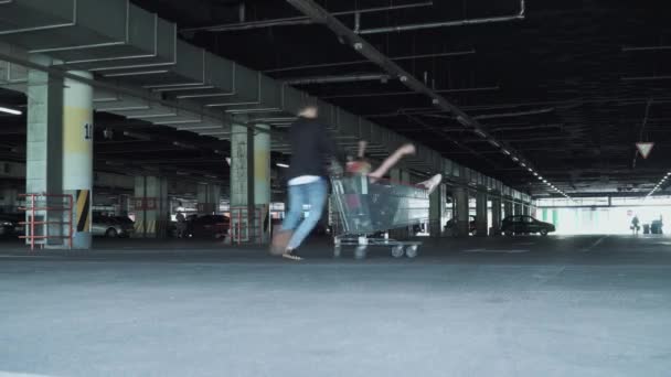 Man Rolt Vrouw Trolley Van Supermarkt Ondergrondse Parkeergarage Man Rijdt — Stockvideo