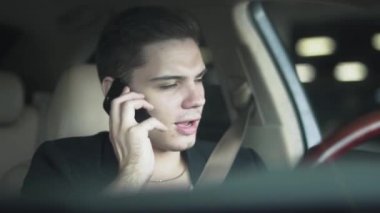 Arabada sakız çiğneyen ve cep telefonuyla konuşan genç bir adamın portresi. Zengin, kendine güvenen iş adamının keyfi.