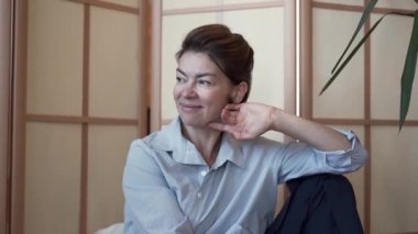 Modern tasarımile odada oturan arkadaşı ile konuşurken zarif iyi giyimli olgun bayan Portresi. Evde dinlenen kadın. Sağlıklı yaşam, dinlenme, mutlu bir hayat. Yavaş çekim.