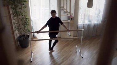 Sevimli esnek olgun kadın evde pratik. Siyah giysiler içinde zarif ince kadın kapalı egzersizleri yapıyor. Mutlu yaşam, formda tutmak.