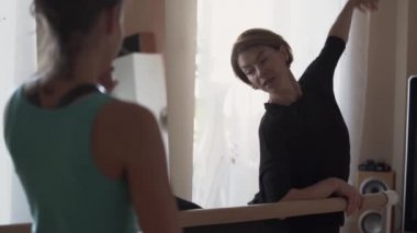 Profesyonel esnek kadın eğitmen nasıl bacaklarını germek için kız gösteren. Fitness eğitmeni evde ya da stüdyoda genç kız ile çalışıyor. Aktif yaşam tarzı