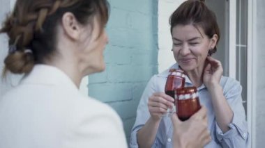 Balkonda dururken şarap içen iki kız arkadaş. Sevimli olgun kadınlar evde birlikte vakit geçiriyorlar. Dostluk, sağlıklı yaşam, mutlu yaşam kavramı.