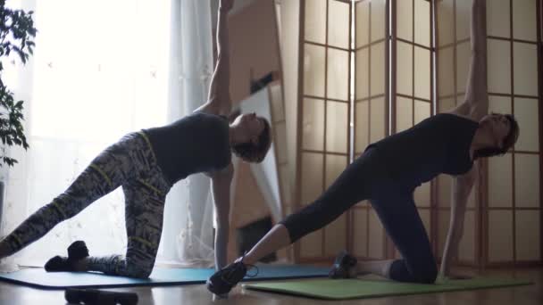 Zwei reife kaukasische Frauen, die zu Hause auf den Matten Übungen auf dem Boden machen. Sportlerinnen dehnen Körper. Gesunder Lebensstil, Erholung, Fitness. — Stockvideo