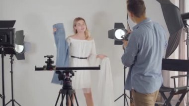 Fotoğraf çekiminin sahne arkası. Fotoğrafçı stüdyoda beyaz arka plan üzerinde poz sevimli kız fotoğrafları çekiyor. Moda dergisi stüdyo photoshoot.