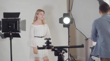 Fotoğraf çekiminin sahne arkası. Fotoğrafçı stüdyoda beyaz arka plan üzerinde poz güzel kız fotoğrafları çekiyor. Moda dergisi stüdyo photoshoot.