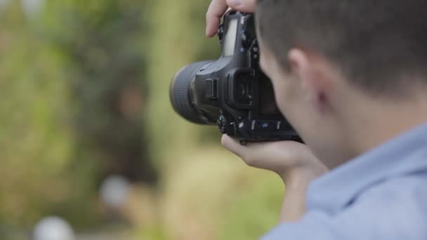 Profesyonel fotoğrafçı açık havada dururken genç kadının fotoğraflarını çekiyor. — Stok video