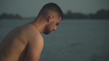 Yakışıklı adam topu ayağıyla dolduruyor. Genç adam ve top. Arka planda nehir.