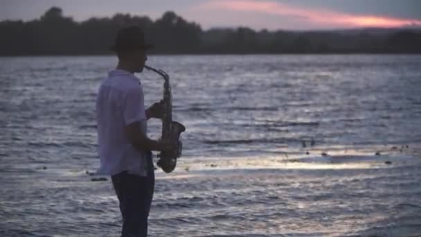 Joven Guapo Toca Saxofón Orilla Del Río Tipo Con Una — Vídeos de Stock