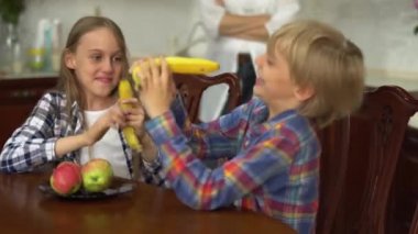 İki tatlı çocuk mutfakta muzla silah gibi oynaşıyor. Kız ve erkek birlikte vakit geçiriyorlar. Sağlıklı bir yaşam tarzı. Tasasız çocukluk