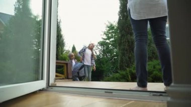 Sırt çantalı küçük yorgun çocuk ve kız eve dönüyorlar. Annem okuldan dönen çocuklarla tanışır. Mutlu sevgi dolu aile kavramı