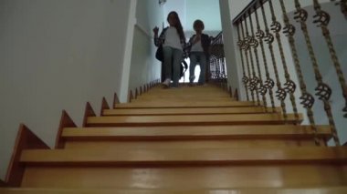 İki mutlu okul çocuğu sırt çantalarıyla merdivenlerden aşağı iniyor. Kardeşler okuldan yeni döndüler. Mutlu dost çocuklar..