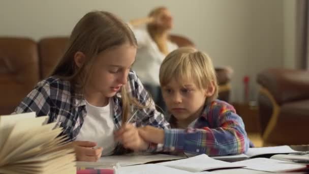 立派な弟と妹が家で勉強している 子供たちは一緒に宿題をする — ストック動画