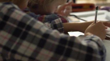 Evde ders çalışan küçük tatlı kız ve oğlanın yakın çekimi. Çocuklar ödevlerini birlikte yapıyorlar. Mutlu kardeşler evde birlikte vakit geçiriyorlar.