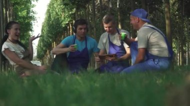 Bahçıvan ekibi işten sonra sahada dinleniyor. İnsanlar bulanık ve bulanık. Erkekler ve kadınlar dostça konuşurlar.