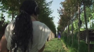 Kahverengi üniformalı kadın bahçede yürüyor. Hanımefendinin elinde birkaç dal var. Kadın mutlu ve gülümsüyor. İşinden zevk alan birinin portresi