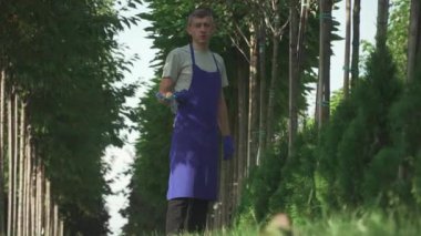 Bahçıvan bahçede çalışıyor. Bahçıvan üniformalı ve bahçe makası ile. Genç bahçıvan çok kızgın..