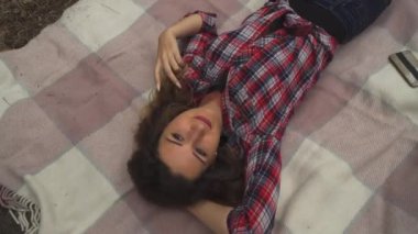 Caucasian dreaming woman on blanket in forest, touching hair, video 