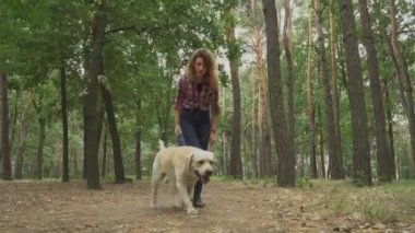 Ormanda köpekle gezen genç bir kadın. 