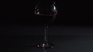 Buz küpü koyu arkaplanda bir kadeh şaraba düşer. 