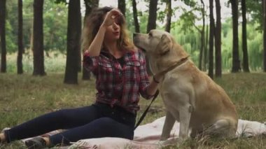 Genç bir kadın, köpekle ormanda vakit geçiriyor. 