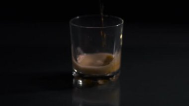 Kola boş bir bardağa dökülüyor. Kola ile kaplanmış koyu bir arka plan. Bir bardak kolada hava kabarcıkları. Yakın plan. Siyah arkaplan.